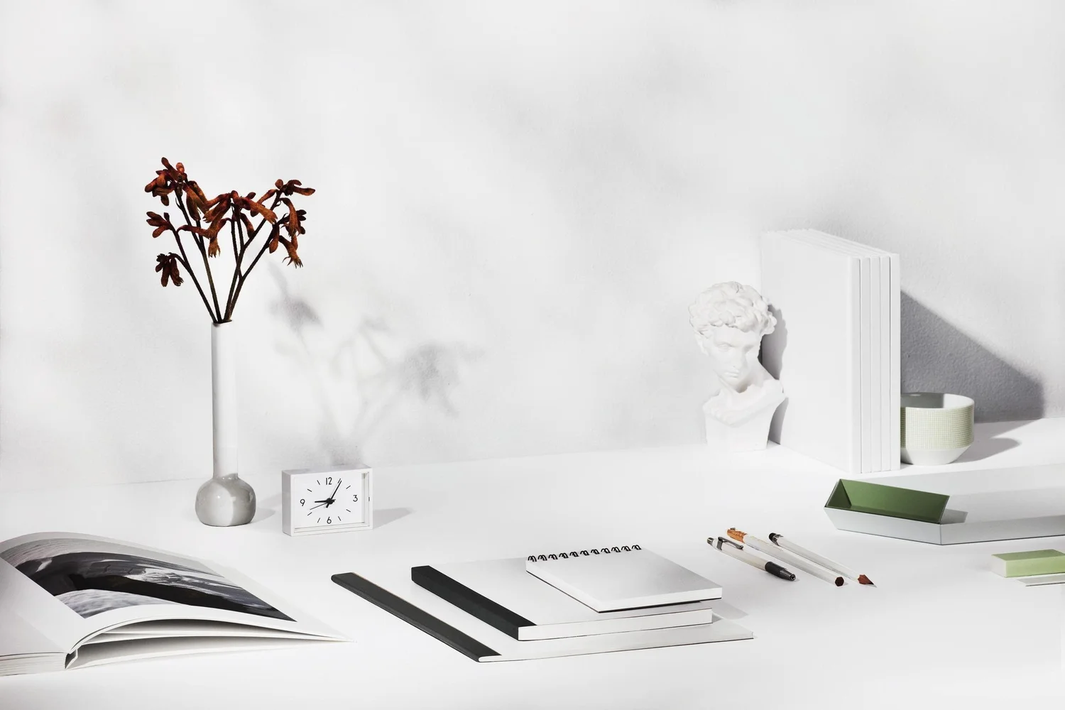 A bright desk with books, flowers, and drawing tools
